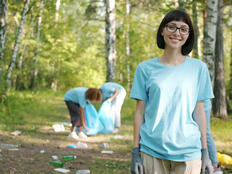 Smiling volunteer in a light blue T-shirt at a park cleanup
