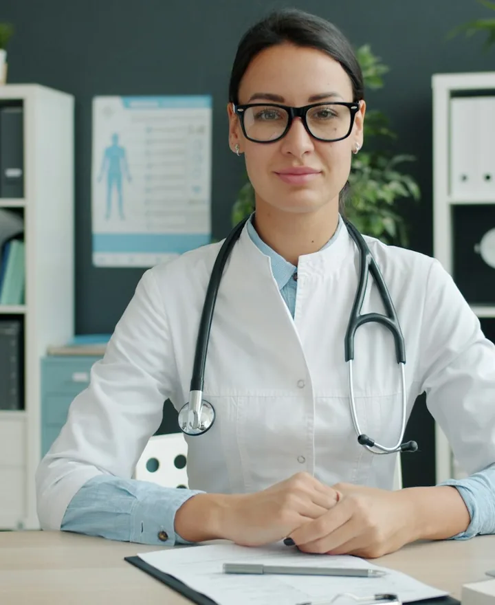 Dr. Maya Chen, lead dentist, smiling at her desk in a white coat