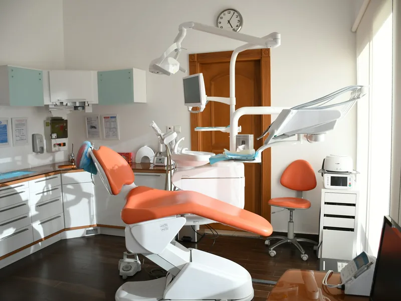 Treatment room with a coral dental chair and soft natural light