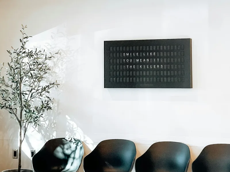 Minimal reception area with an olive tree and black lounge chairs