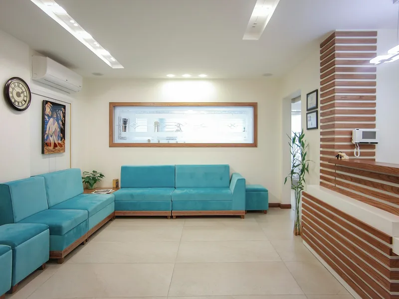 Waiting area with a long teal sofa and warm wood accents