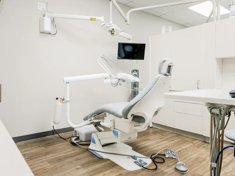 Spotless treatment room with a white chair and wood-look floor